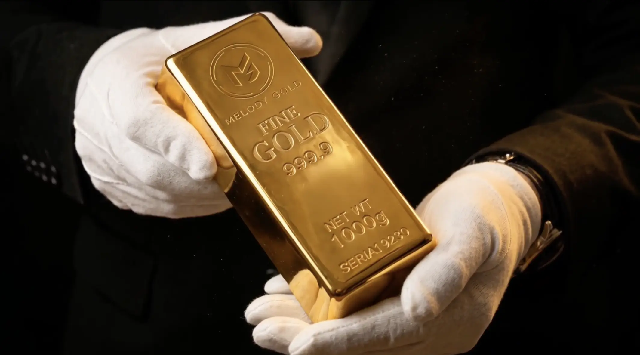 Gloved hands presenting a 1000 g 999.9 fine gold Melody Gold bar